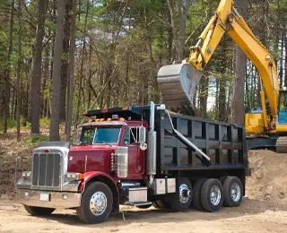 An excavator loads dirt into a dump truck at a job site