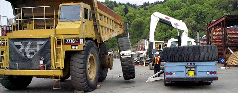 Les Schwab employee changing a tire on a giant dump truck.
