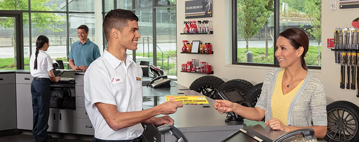 Les Schwab employee handing a customer information about their warranty