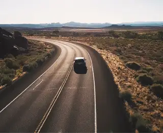 Car rounds the corner on a high desert highway