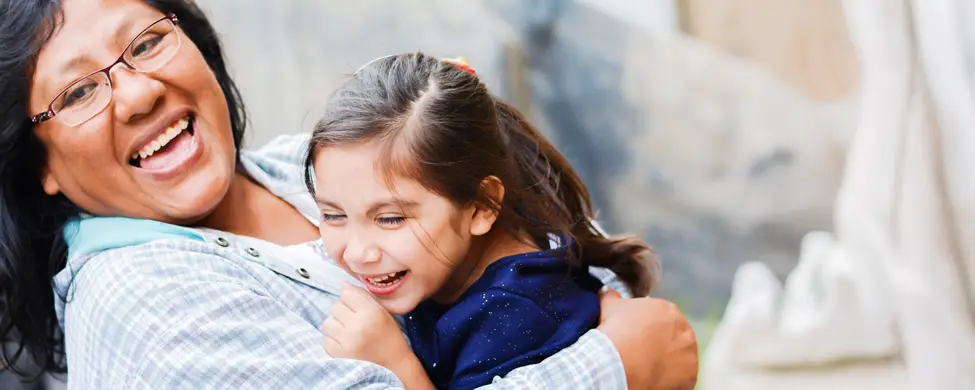 A hispanic mother and daughter laughing.